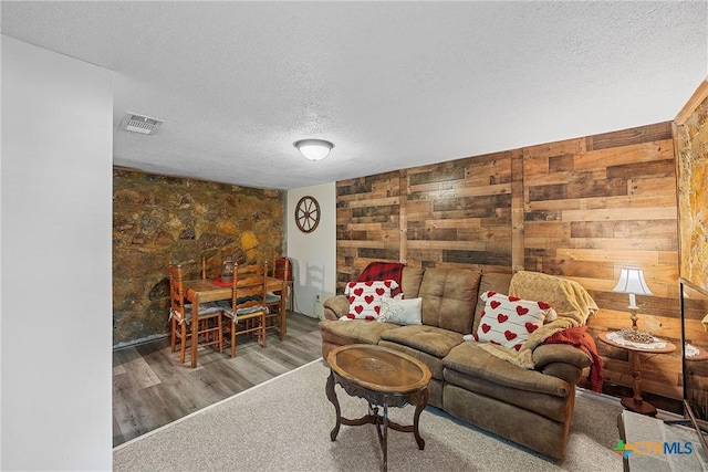 living room with wooden walls and a textured ceiling