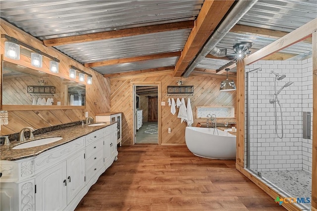 bathroom featuring beam ceiling, plus walk in shower, wood walls, wood-type flooring, and vanity