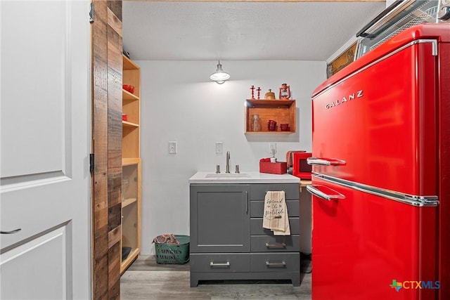 interior space with high end refrigerator, dark hardwood / wood-style flooring, gray cabinetry, a textured ceiling, and sink