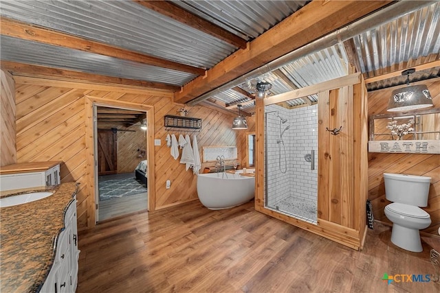 bathroom with a bathtub, vanity, hardwood / wood-style flooring, beamed ceiling, and toilet