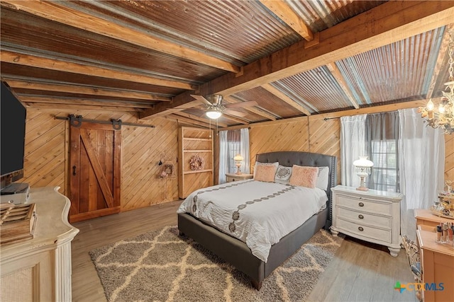 bedroom featuring beam ceiling, hardwood / wood-style flooring, ceiling fan, and wooden walls