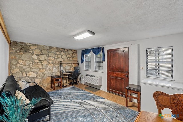 sitting room with a wall mounted air conditioner, light tile patterned floors, and a textured ceiling