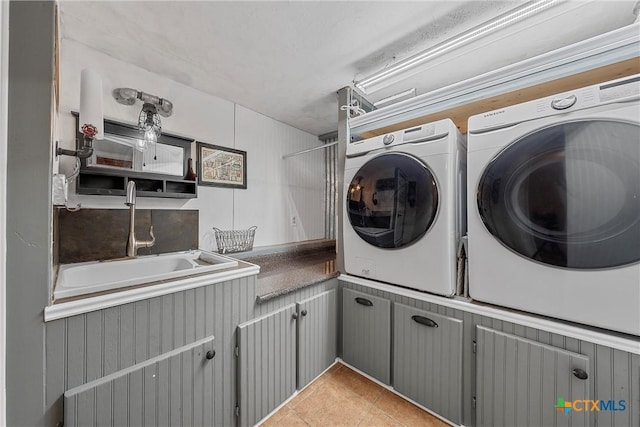 laundry area with washer and dryer, cabinets, light tile patterned floors, and sink