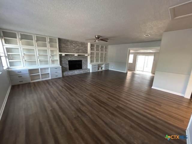 unfurnished living room featuring a fireplace, a textured ceiling, dark hardwood / wood-style flooring, and ceiling fan