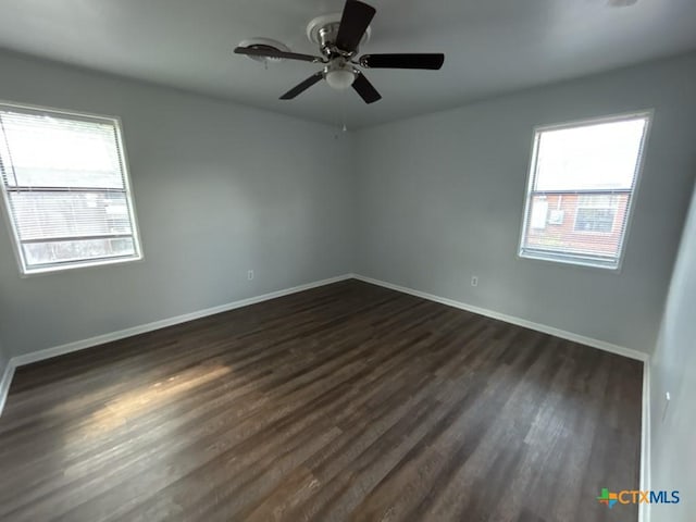 spare room with a wealth of natural light, dark wood-type flooring, and ceiling fan