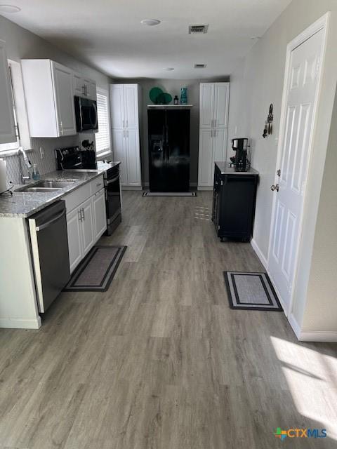 kitchen with white cabinets, wood-type flooring, sink, and black appliances