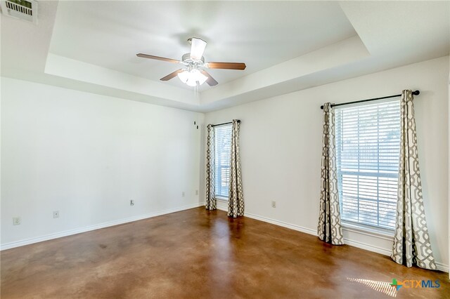 unfurnished room with ceiling fan and a tray ceiling