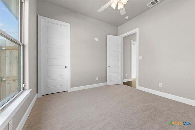 unfurnished bedroom with a ceiling fan, carpet flooring, visible vents, and baseboards