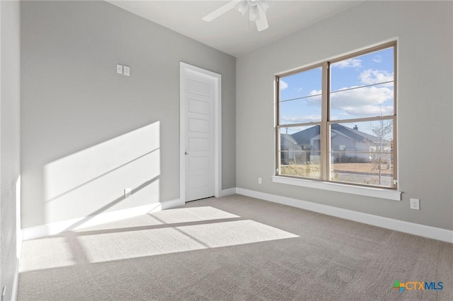 carpeted spare room featuring ceiling fan, baseboards, and a wealth of natural light