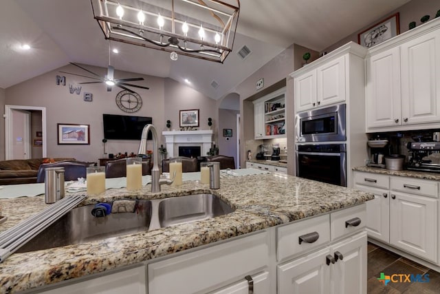 kitchen with sink, white cabinetry, hanging light fixtures, stainless steel appliances, and light stone countertops