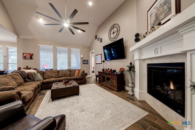 living room featuring ceiling fan, lofted ceiling, and a tiled fireplace