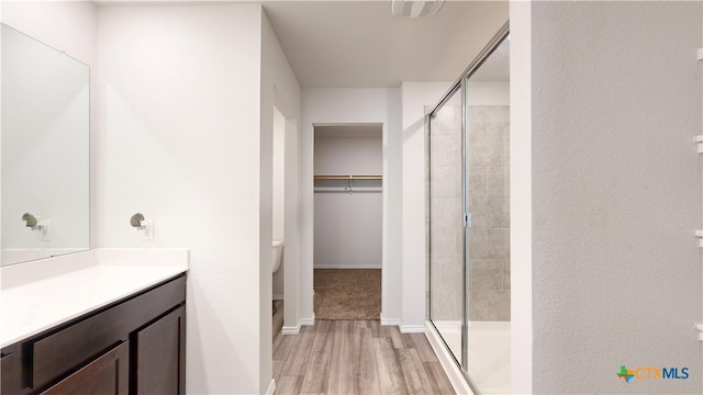 1519 Merritt St, Temple, TX 76504 - full bathroom featuring wood finished floors, a stall shower, toilet, vanity, and a spacious closet