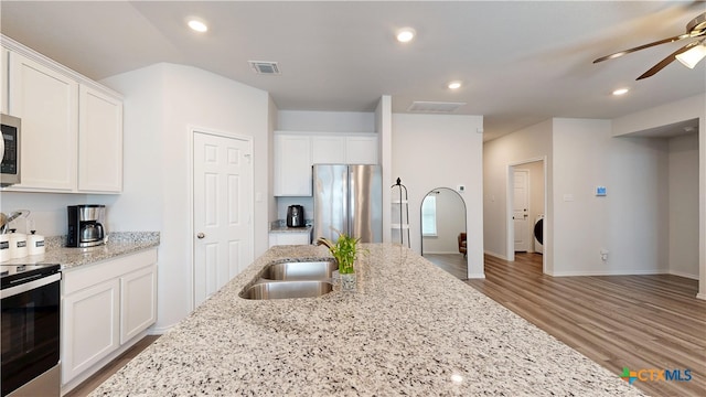 1519 Merritt St, Temple, TX 76504 - kitchen with stainless steel appliances, a ceiling fan, light wood-type flooring, a sink, and white cabinetry