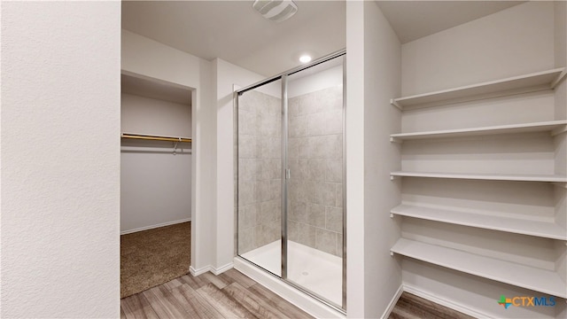 1519 Merritt St, Temple, TX 76504 - full bathroom featuring wood finished floors, a stall shower, a walk in closet, and baseboards
