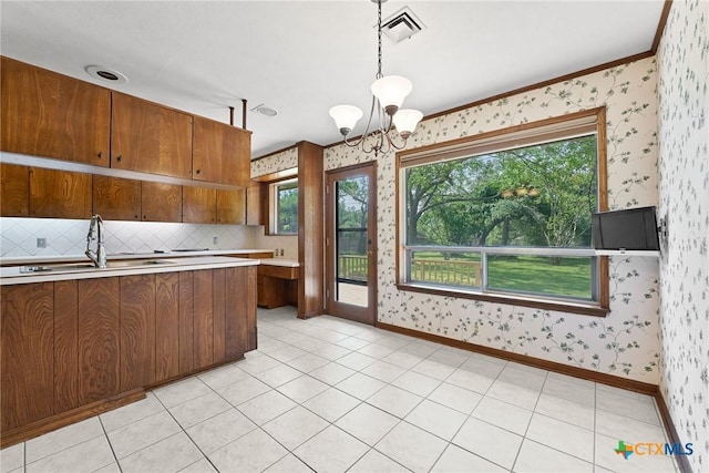 517 Cherokee Dr, Temple, TX 76504 - kitchen featuring brown cabinets, wallpapered walls, light countertops, visible vents, and a sink