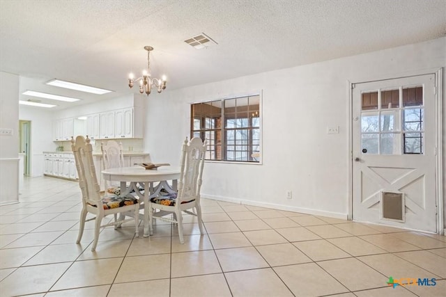 unfurnished dining area featuring a healthy amount of sunlight, light tile patterned floors, a textured ceiling, and a chandelier