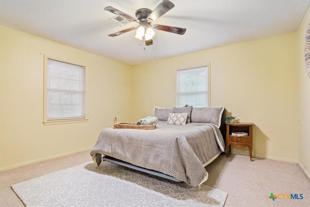 carpeted bedroom with ceiling fan and a textured ceiling