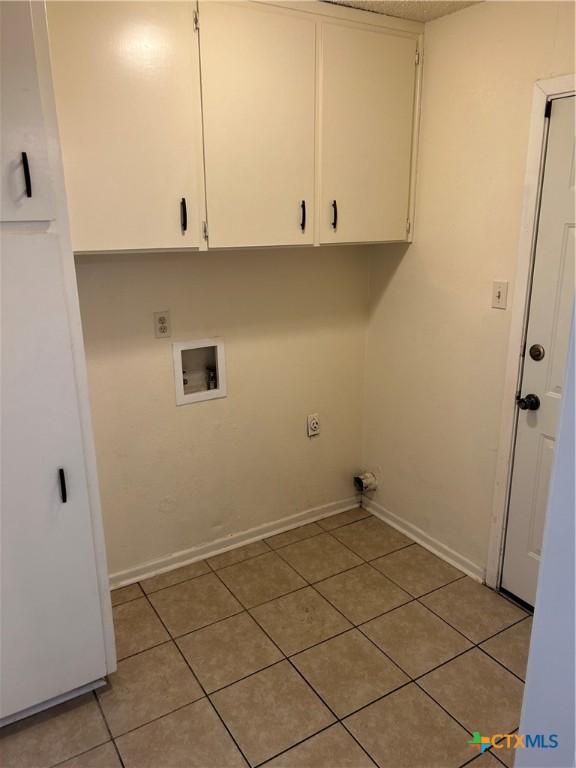 laundry area featuring electric dryer hookup, cabinet space, light tile patterned flooring, baseboards, and hookup for a washing machine