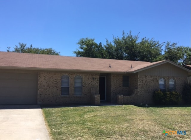 ranch-style home with brick siding, a garage, concrete driveway, and a front yard