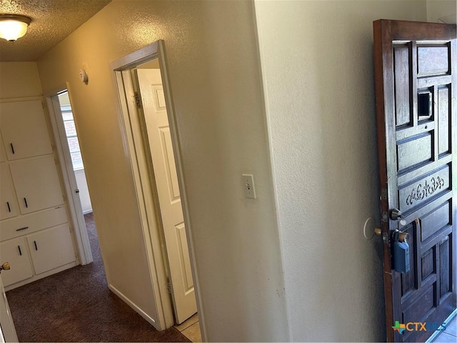 foyer entrance featuring carpet, a textured wall, and a textured ceiling