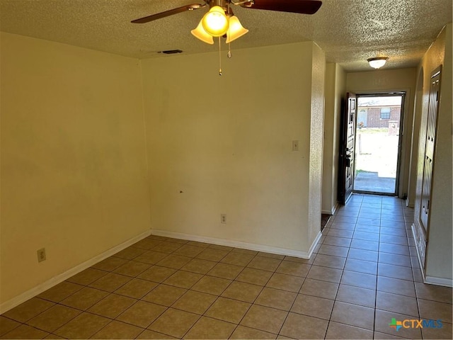 tiled spare room with visible vents, a textured ceiling, baseboards, and a ceiling fan