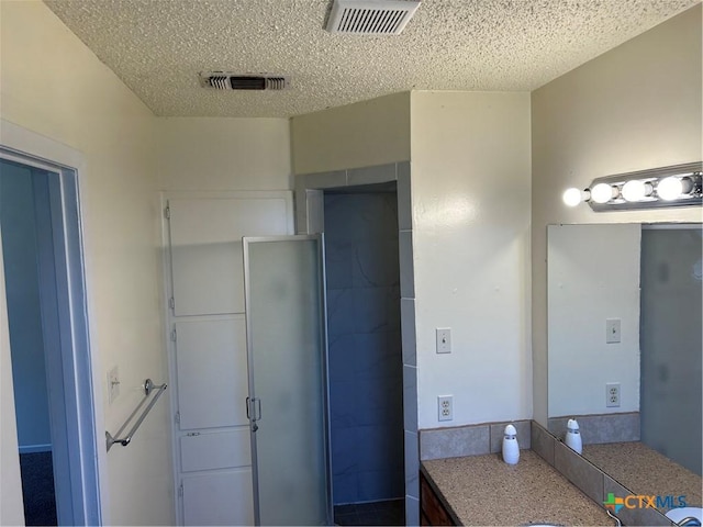 full bath with visible vents, a textured ceiling, and a shower stall