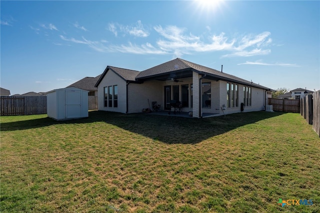 back of house with ceiling fan, a storage shed, a patio area, and a lawn