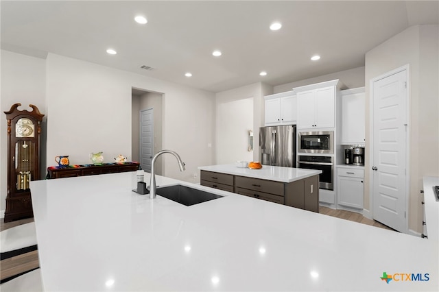 kitchen with a breakfast bar, a center island, white cabinets, sink, and appliances with stainless steel finishes