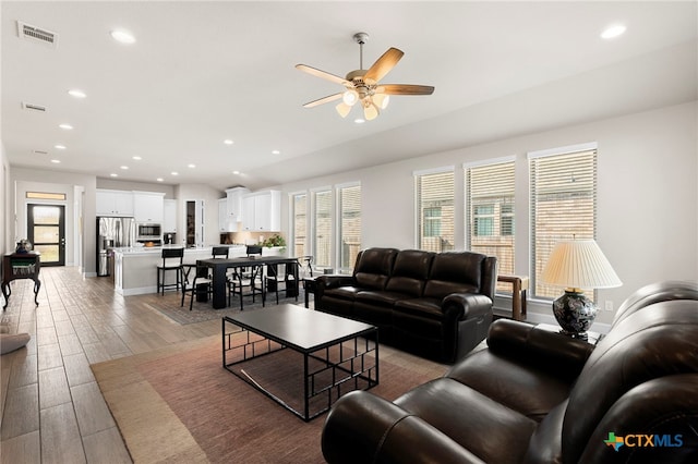 living room featuring ceiling fan and a healthy amount of sunlight