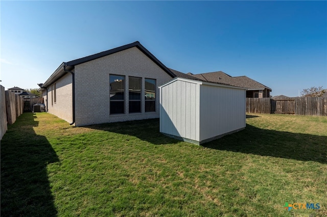 back of house with a yard, cooling unit, and a storage unit