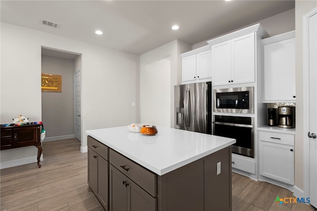 kitchen featuring a center island, white cabinets, stainless steel appliances, and light hardwood / wood-style floors