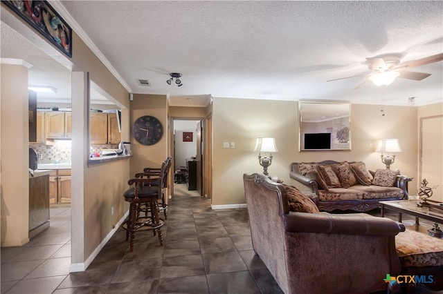 tiled living room with a textured ceiling, ceiling fan, and crown molding