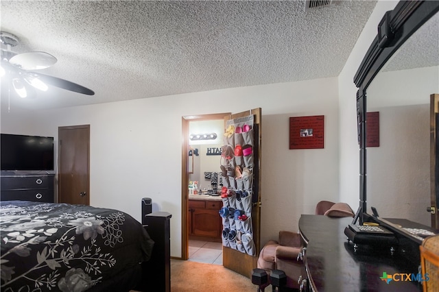 tiled bedroom featuring a textured ceiling, ensuite bath, and ceiling fan