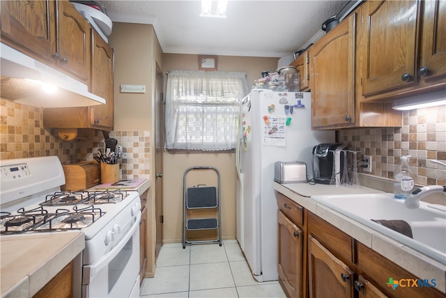 kitchen featuring light tile patterned flooring, sink, a textured ceiling, white appliances, and decorative backsplash