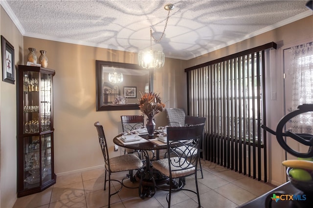 tiled dining space with a textured ceiling, crown molding, and a notable chandelier