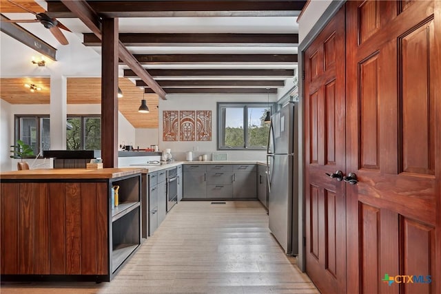 kitchen with freestanding refrigerator, a peninsula, light countertops, light wood-style floors, and open shelves