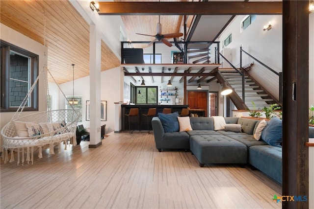 interior space with hardwood / wood-style flooring, high vaulted ceiling, beamed ceiling, and ceiling fan with notable chandelier