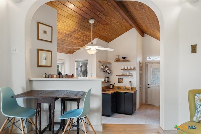 interior space featuring light wood finished floors, arched walkways, wood ceiling, vaulted ceiling with beams, and wet bar