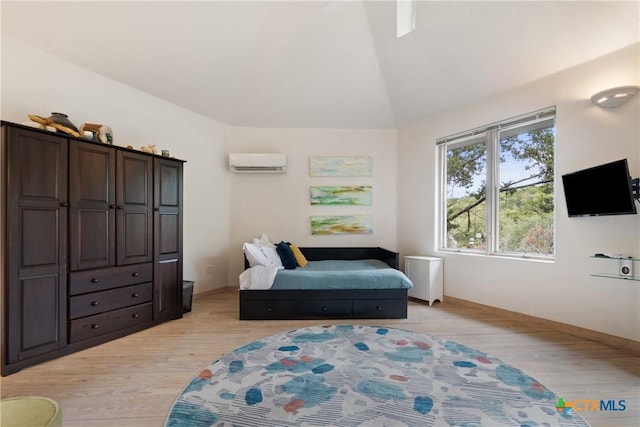 living area with a wall mounted air conditioner, vaulted ceiling, and light wood-style flooring