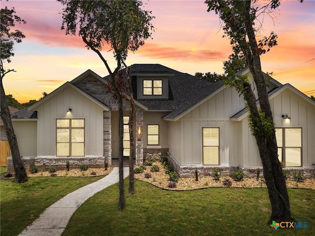 modern inspired farmhouse featuring stone siding, a lawn, and board and batten siding