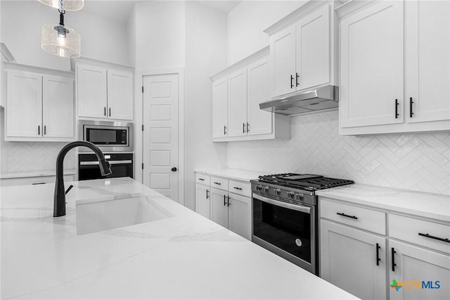 kitchen with under cabinet range hood, stainless steel appliances, a sink, white cabinets, and backsplash