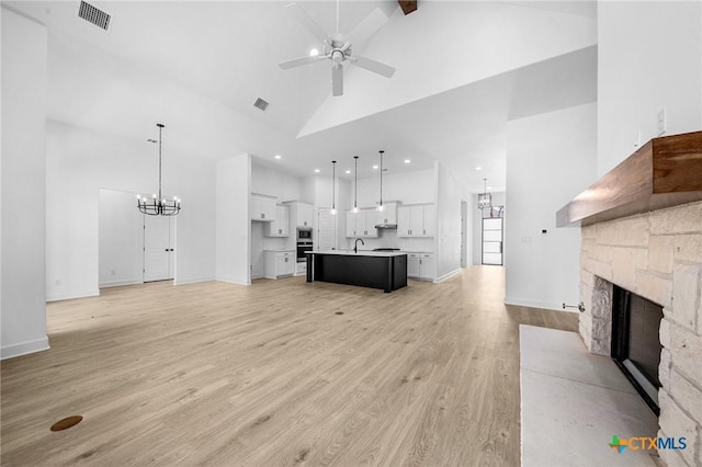 unfurnished living room featuring light wood finished floors, visible vents, a fireplace, and high vaulted ceiling