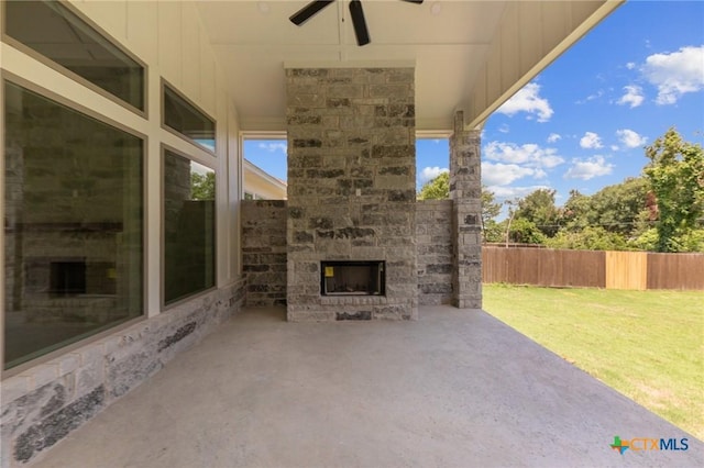 view of patio / terrace with ceiling fan, fence, and an outdoor stone fireplace