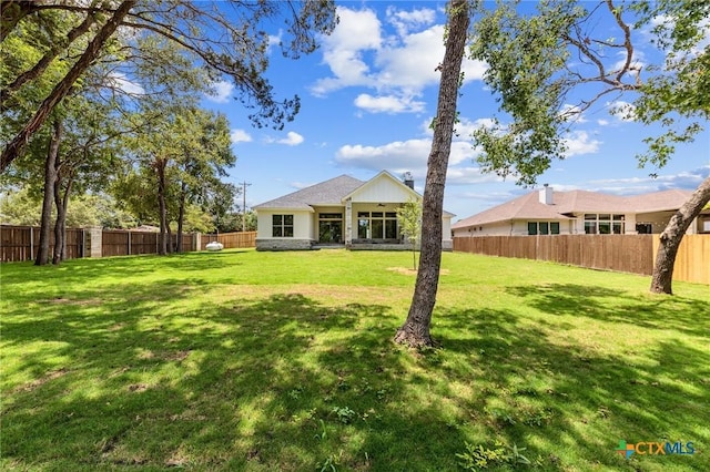 back of property featuring a fenced backyard and a lawn