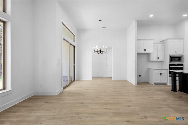 kitchen featuring black oven, stainless steel microwave, white cabinets, and a healthy amount of sunlight