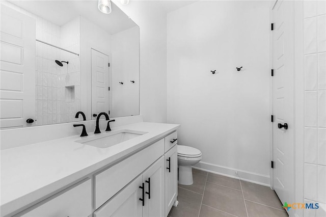 bathroom with tile patterned flooring, toilet, vanity, baseboards, and walk in shower