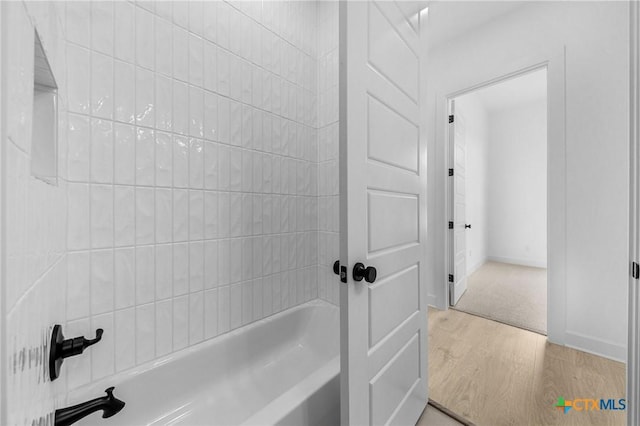 bathroom featuring washtub / shower combination and wood finished floors