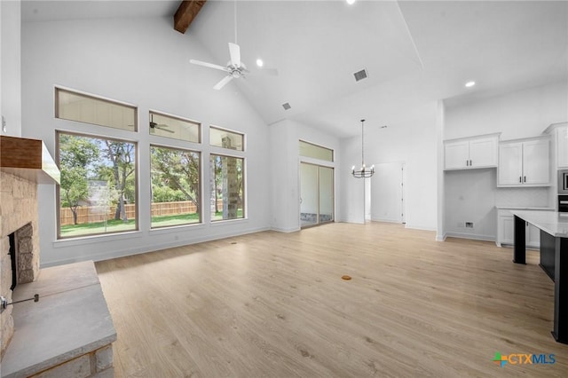 unfurnished living room with a fireplace, visible vents, high vaulted ceiling, light wood-type flooring, and beamed ceiling