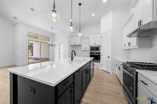 kitchen with visible vents, white cabinets, stainless steel appliances, dark cabinetry, and a sink