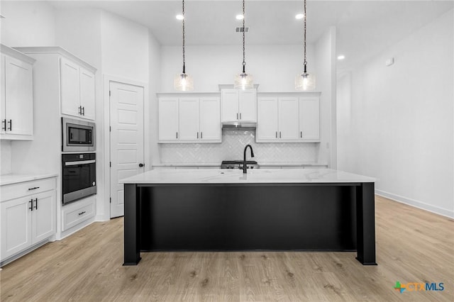 kitchen with light wood finished floors, white cabinetry, stainless steel appliances, and backsplash